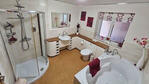 Een moderne badkamer met een douche, wastafel, toilet en bad.
