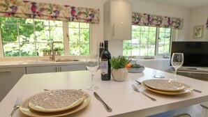 Une cuisine avec un coin repas, comprenant un grand îlot central avec des assiettes, des couverts et une bouteille de vin.