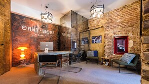 A modern office space with a brick wall, a desk with a computer, a chair, and a lamp. - East-West Boutique Hotel Budapest (Budapest)