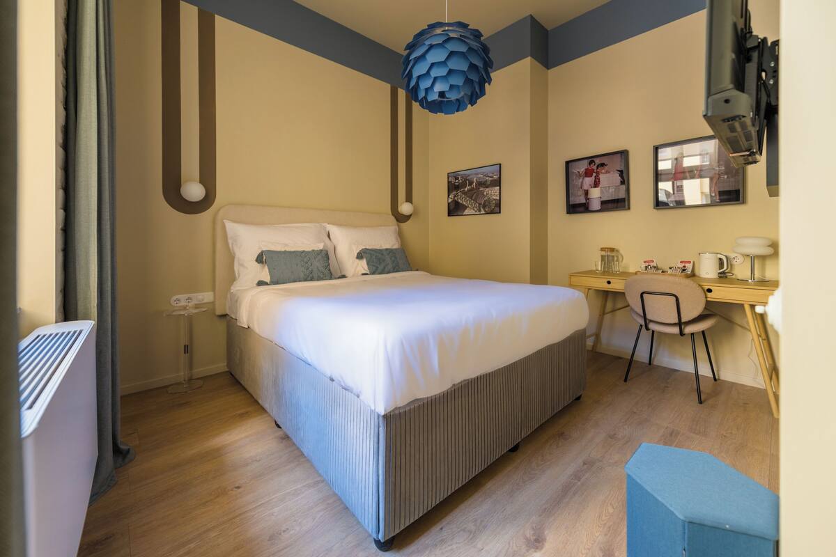 A bedroom with a bed, a desk, and a chair.