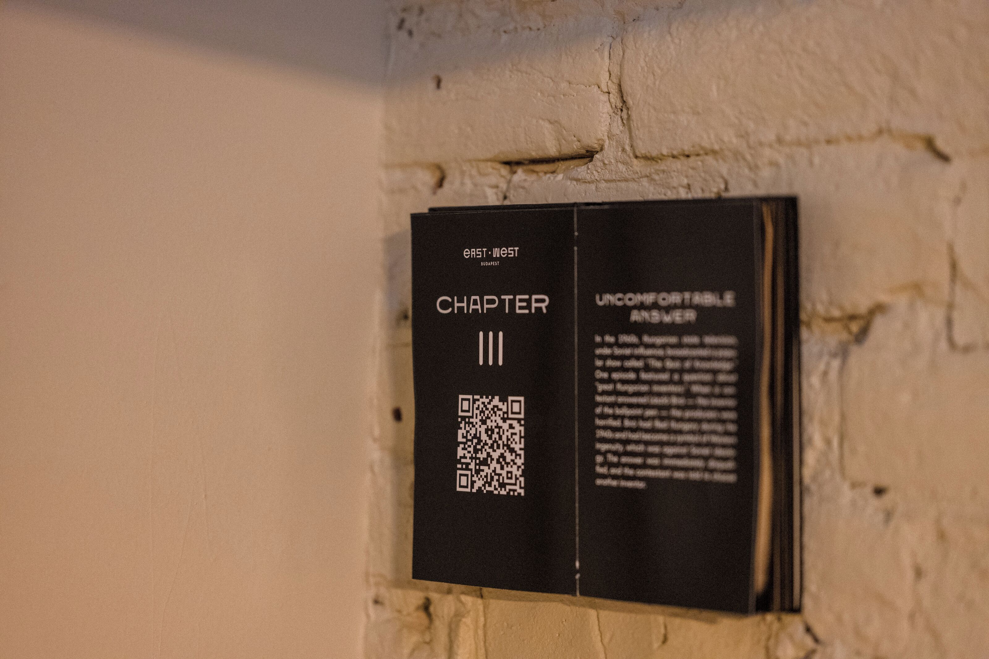 A black plaque with text and a QR code on a wall.