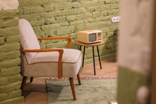 En vintage stol og et lille bord med en radio i et rum med murstensvæg.