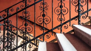 A staircase with ornate black metal railings and a red wall. - East-West Boutique Hotel Budapest (Budapest)