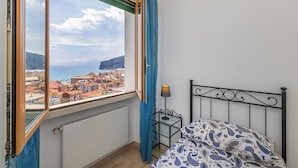 Een slaapkamer met een bed, een nachtkastje, een lamp en een raam met gordijnen.