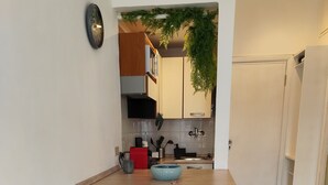 Uma cozinha compacta com uma ilha central, dois bancos altos e uma pia visível.