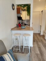A compact kitchen with a central island, two bar stools, and a visible sink.