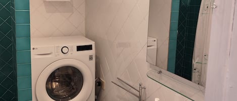 A compact bathroom with a washing machine, two bidets, a sink, and a mirror.