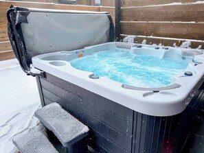 A hot tub with a bench, surrounded by snow.