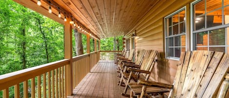 A wooden deck with benches, a railing, and a view of the forest.