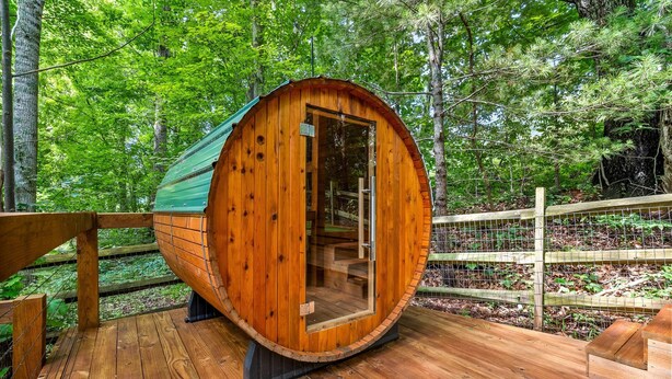 A wooden cabin with a glass door, surrounded by a wooden deck and a wire fence. - 15 MINUTES FROM ASHEVILLE! Secluded peacefull LOG CABIN (Leicester)