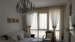 Een woonkamer met een bank, fauteuils, een salontafel en een kroonluchter.
