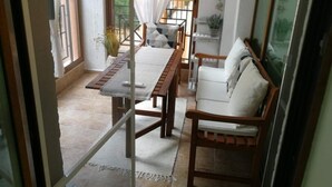 Een kamer met een houten tafel, een witte bank en een raam met gordijnen.