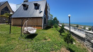Une maison moderne avec un toit en pente, un fauteuil suspendu et une vue sur la mer.