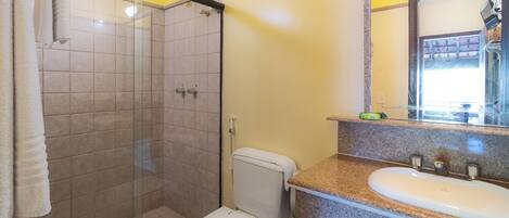 Un bagno con cabina doccia in vetro, un water e un lavabo con piano in granito.