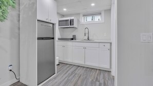 A modern kitchen with white cabinetry, a built-in microwave, and a stainless steel refrigerator. - Luxury Basement Suite in Top Prime Location (Winnipeg)
