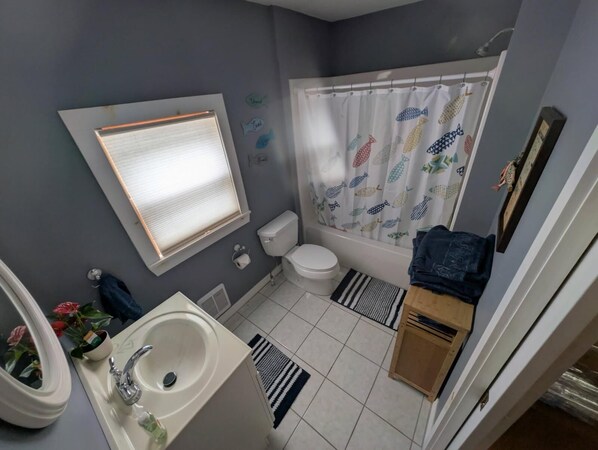 A compact bathroom with a toilet, sink, and shower curtain.