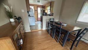 Una cocina con armarios de madera, una mesa de comedor con sillas y una planta en maceta.