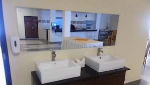 A bathroom with two white sinks, a dark wooden vanity, and a mirror above the sinks. - Silver Side Hotel (Nakuru)