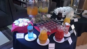 A buffet table with various food and drink options, including a water dispenser, fruit juices, and a selection of yoghurts. - Silver Side Hotel (Nakuru)