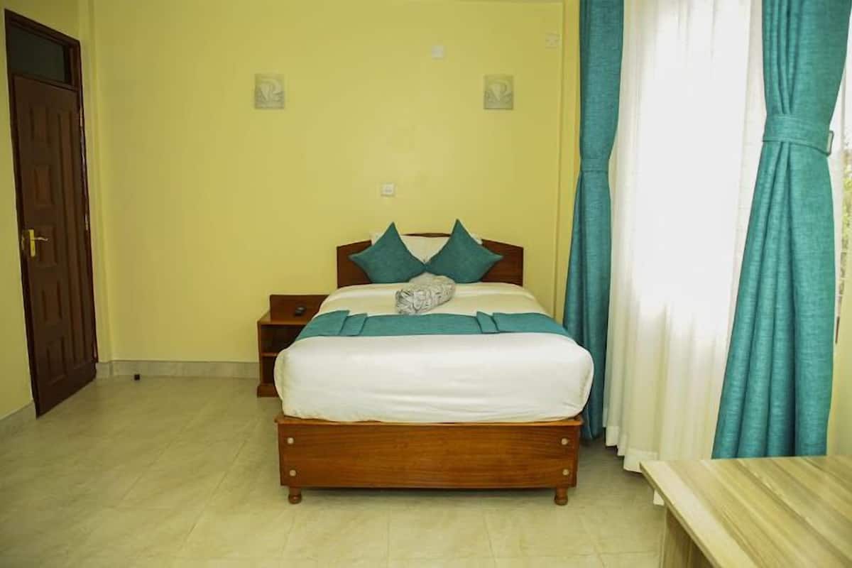 Une chambre à coucher avec un lit en bois, des coussins turquoise et une couette blanche.