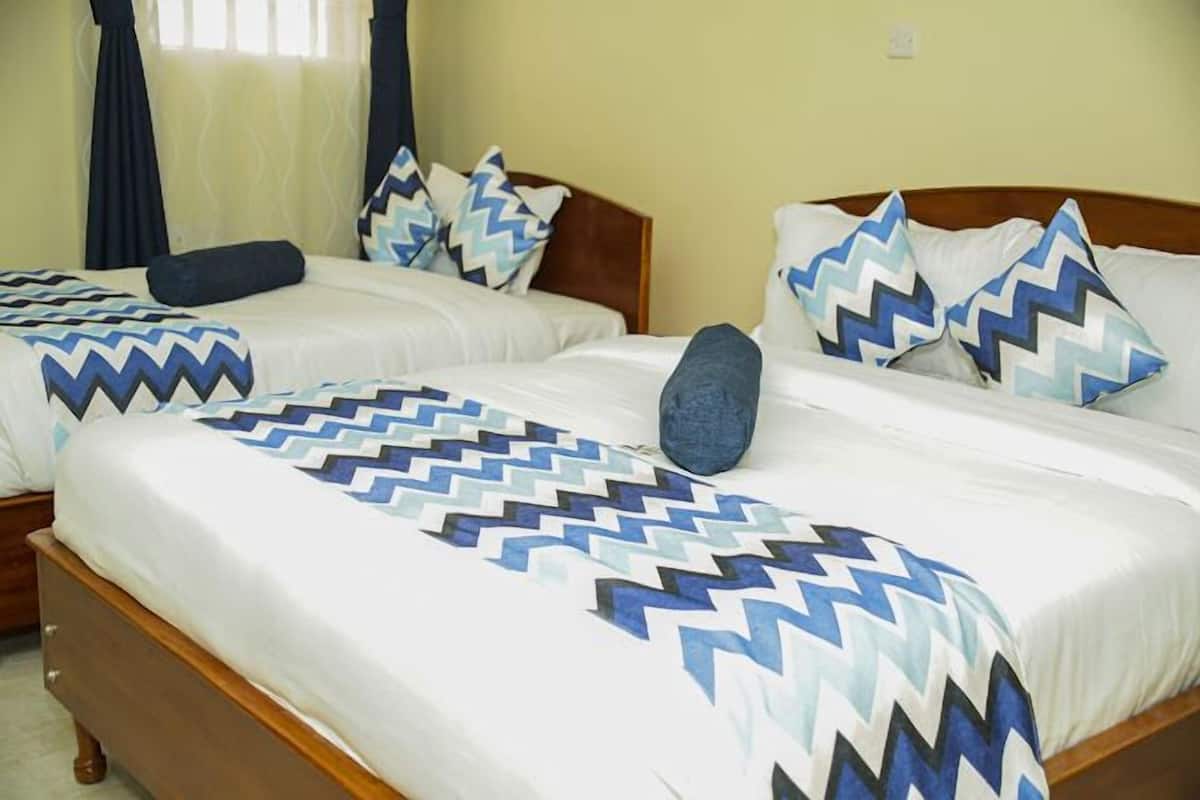 Une chambre d’hôtel avec deux lits, chacun recouvert d’une couvre-lit à motifs et agrémenté d’oreillers assortis.