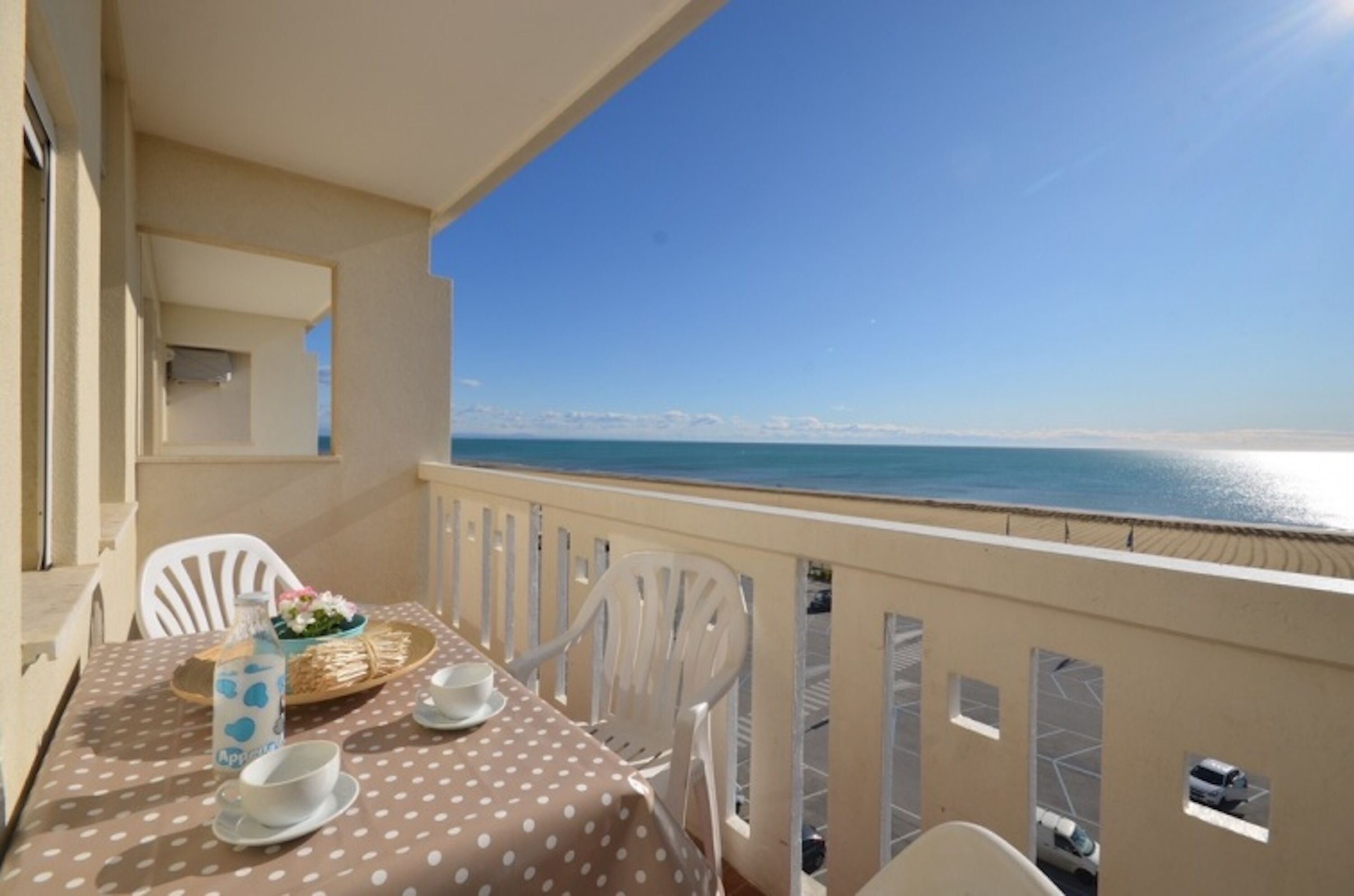 Un balcon avec une table dressée pour deux personnes, donnant sur une plage.
