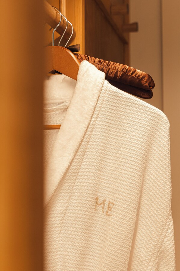 A white towel with a textured pattern and a brown towel on a wooden hanger in a bathroom.