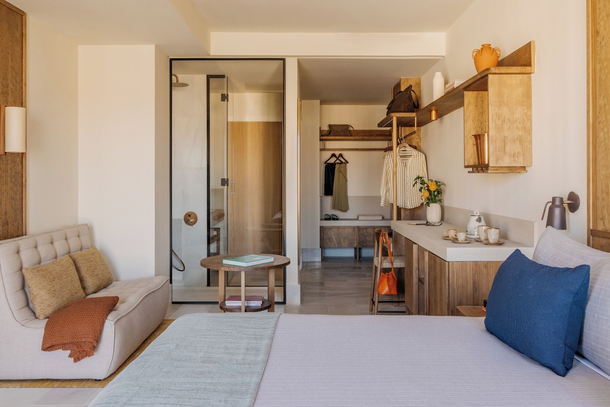 Een moderne hotelkamer met een bed, een bank, een kleine tafel, een bureau en een kitchenette.