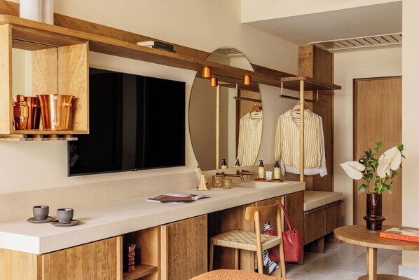 A modern bathroom with a wooden vanity, a mirror, a sink, and a small table with a vase of flowers.
