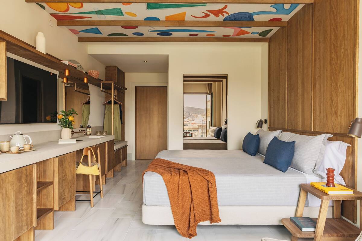 Un dormitorio moderno con una cama grande, un escritorio de madera y vistas a la ciudad.
