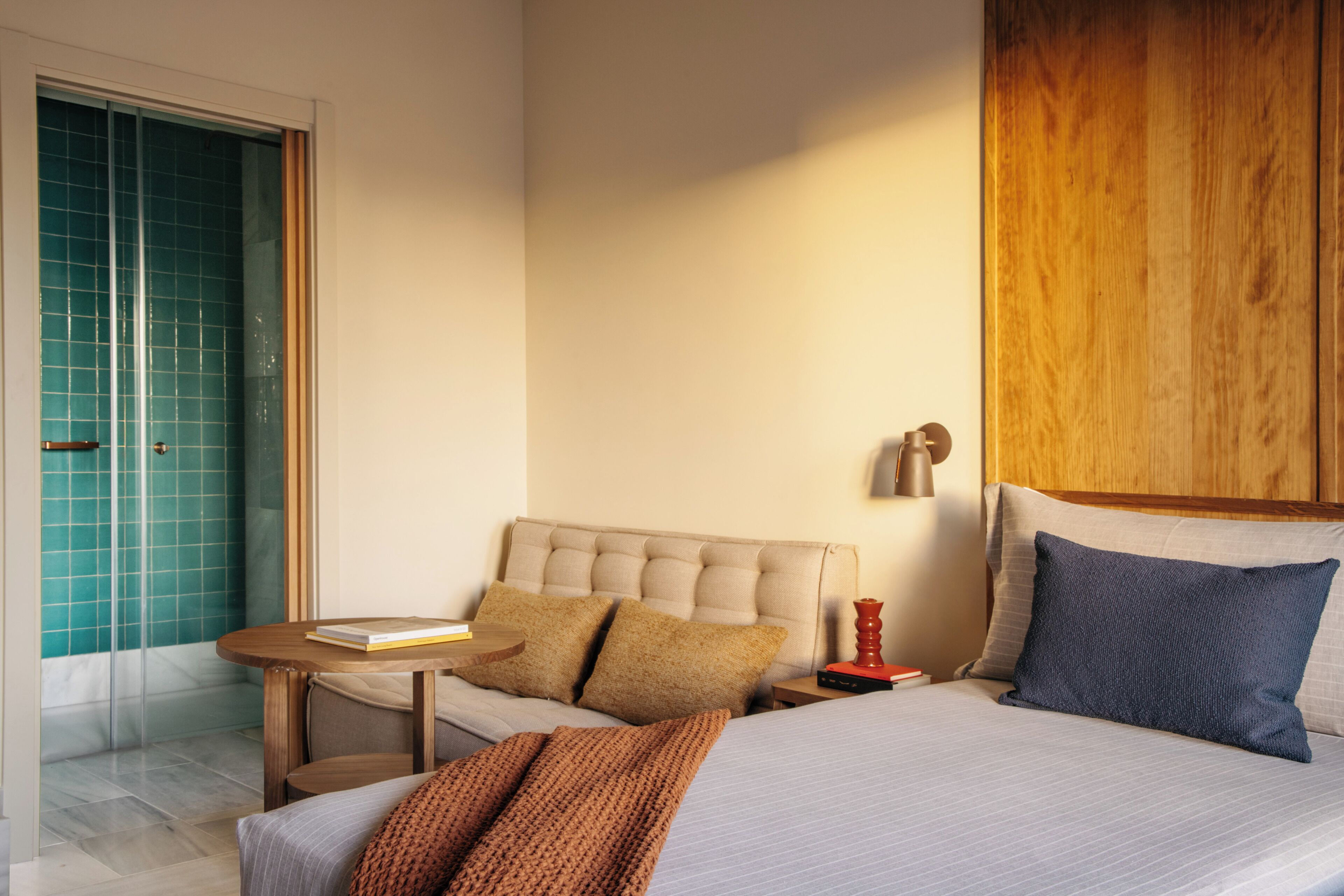 A hotel room with a bed, a small table, a nightstand, and a wooden headboard.