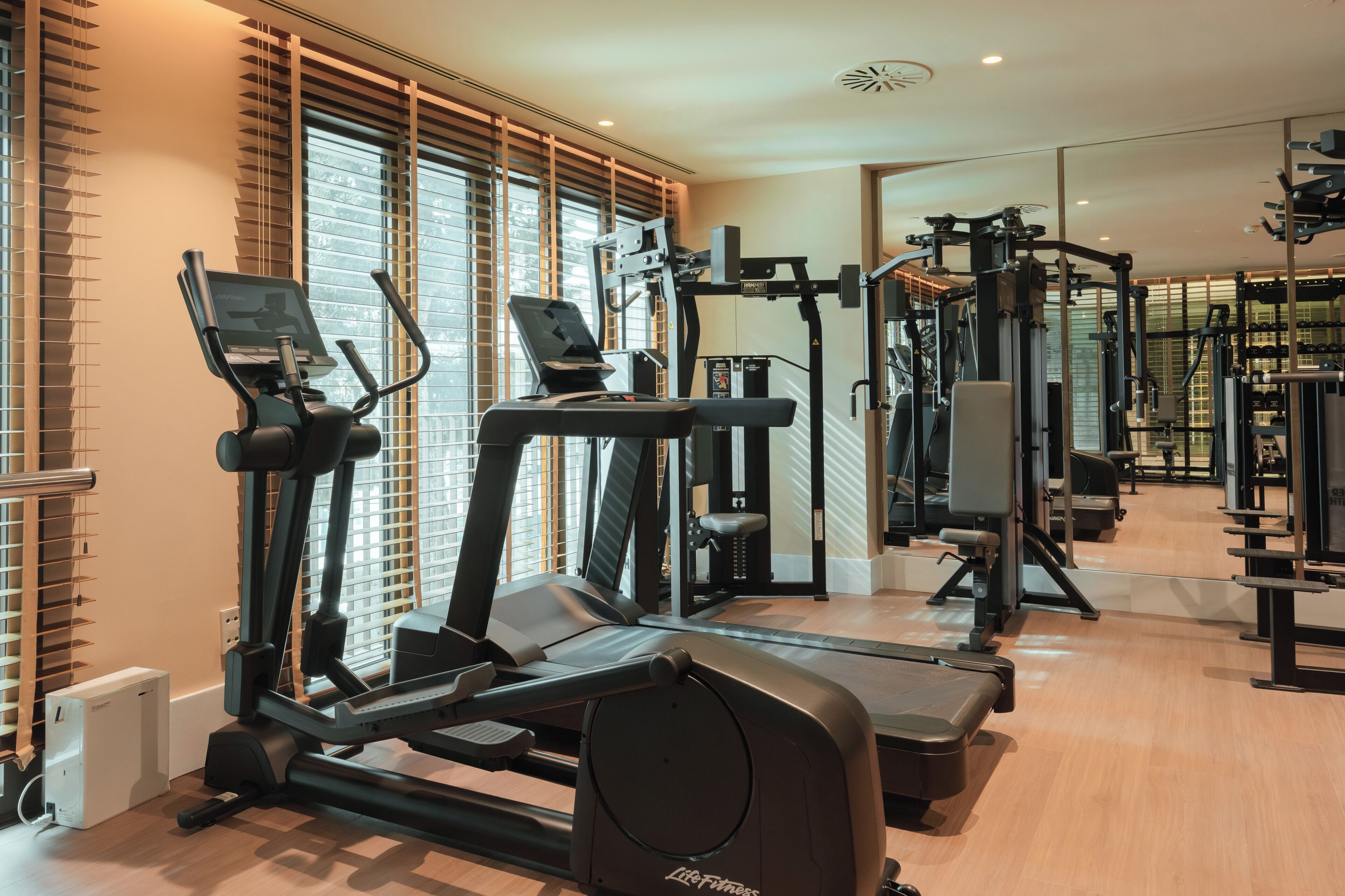 Un gimnasio con cintas de correr, elípticas y equipo de pesas.