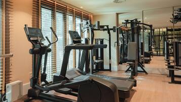 Un gimnasio con cintas de correr, elípticas y equipo de pesas.