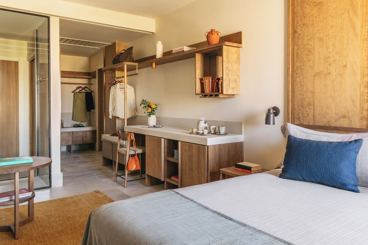 Een moderne hotelkamer met een bed, bureau en kitchenette.