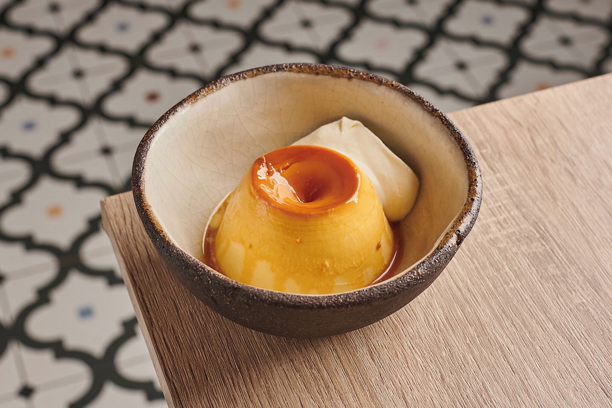 Un dessert servi dans un bol en céramique, posé sur une table en bois.
