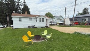 A residential area with a grassy lawn, a metal fire pit, and outdoor chairs. - Darlington River View House - Direct Trail Access (Darlington)