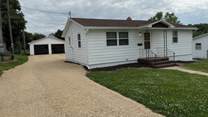 A single-story white house with a front porch, a garage, and a gravel driveway. - Darlington River View House - Direct Trail Access (Darlington)