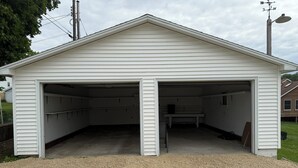 A white garage with two open doors, a gravel driveway, and a wooden fence in the background. - Darlington River View House - Direct Trail Access (Darlington)