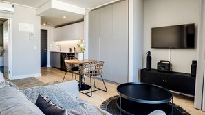 A modern living room with a sofa, a round black table, and a kitchen in the background.