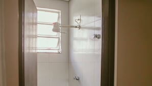 Un baño pequeño con inodoro, ducha y ventana.