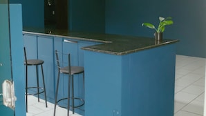 Una cocina con una isla azul, dos taburetes de bar y una planta en maceta.