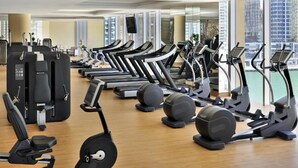 Een sportschool met rijen loopbanden, elliptische trainers en krachtapparaten.