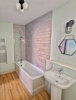 A bathroom with a bathtub, a shower, and a sink.