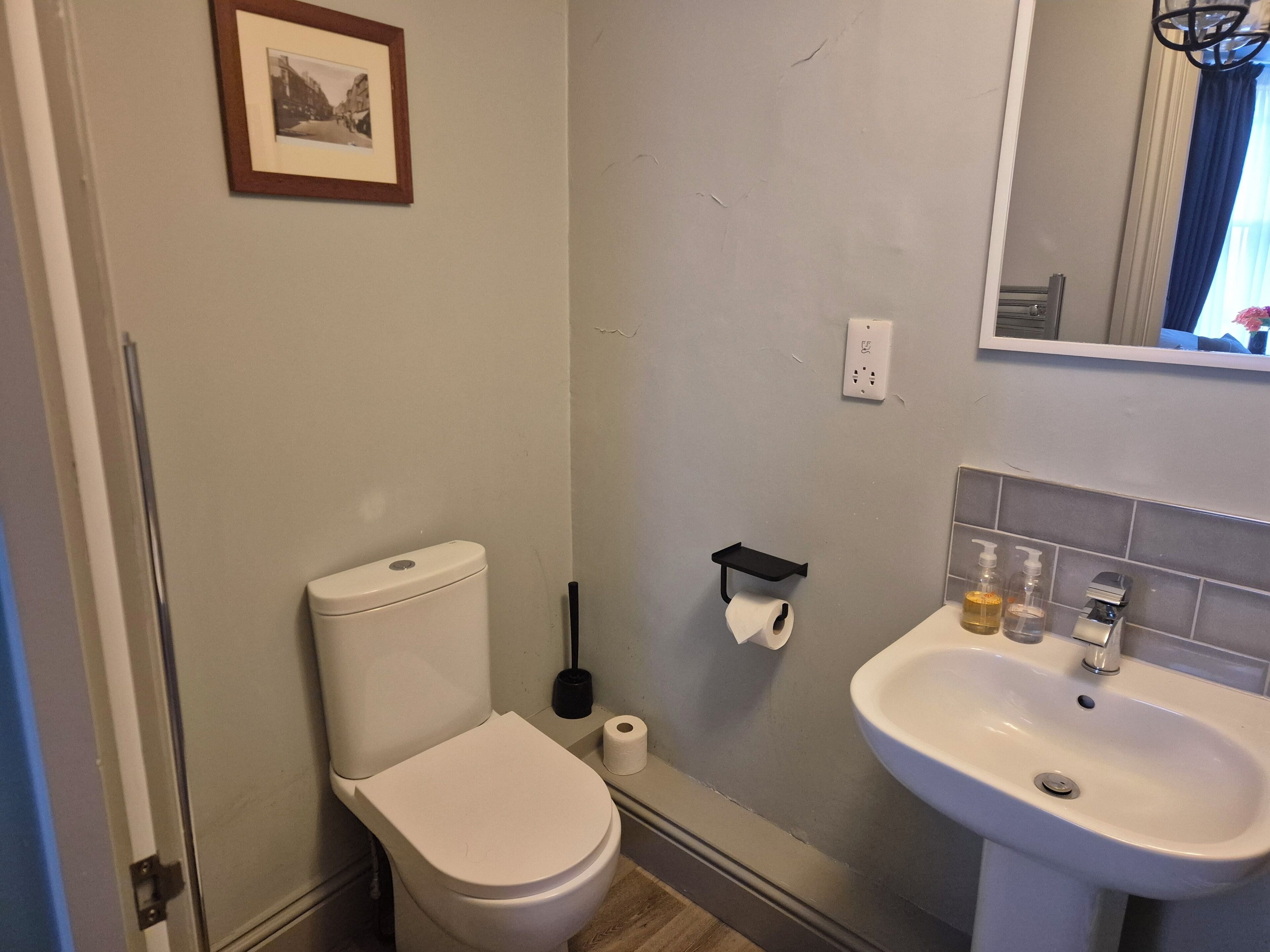 Un bagno con il water, un lavandino, uno specchio e un quadro appeso al muro.