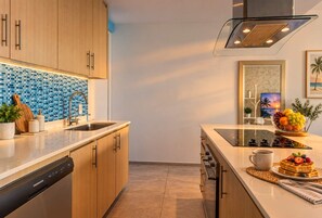 A modern kitchen with wooden cabinets, a stainless steel sink, and a built-in stove. - Golden Hour & Ocean Views (Nuevo Vallarta)