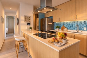 A modern kitchen with a central island, stainless steel appliances, and a blue mosaic backsplash. - Golden Hour & Ocean Views (Nuevo Vallarta)