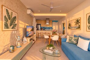 A modern living room with a TV, a glass coffee table, and a blue sofa.