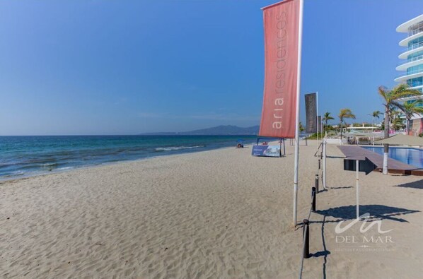 Una playa con cielo despejado, una bandera y un edificio con balcones.