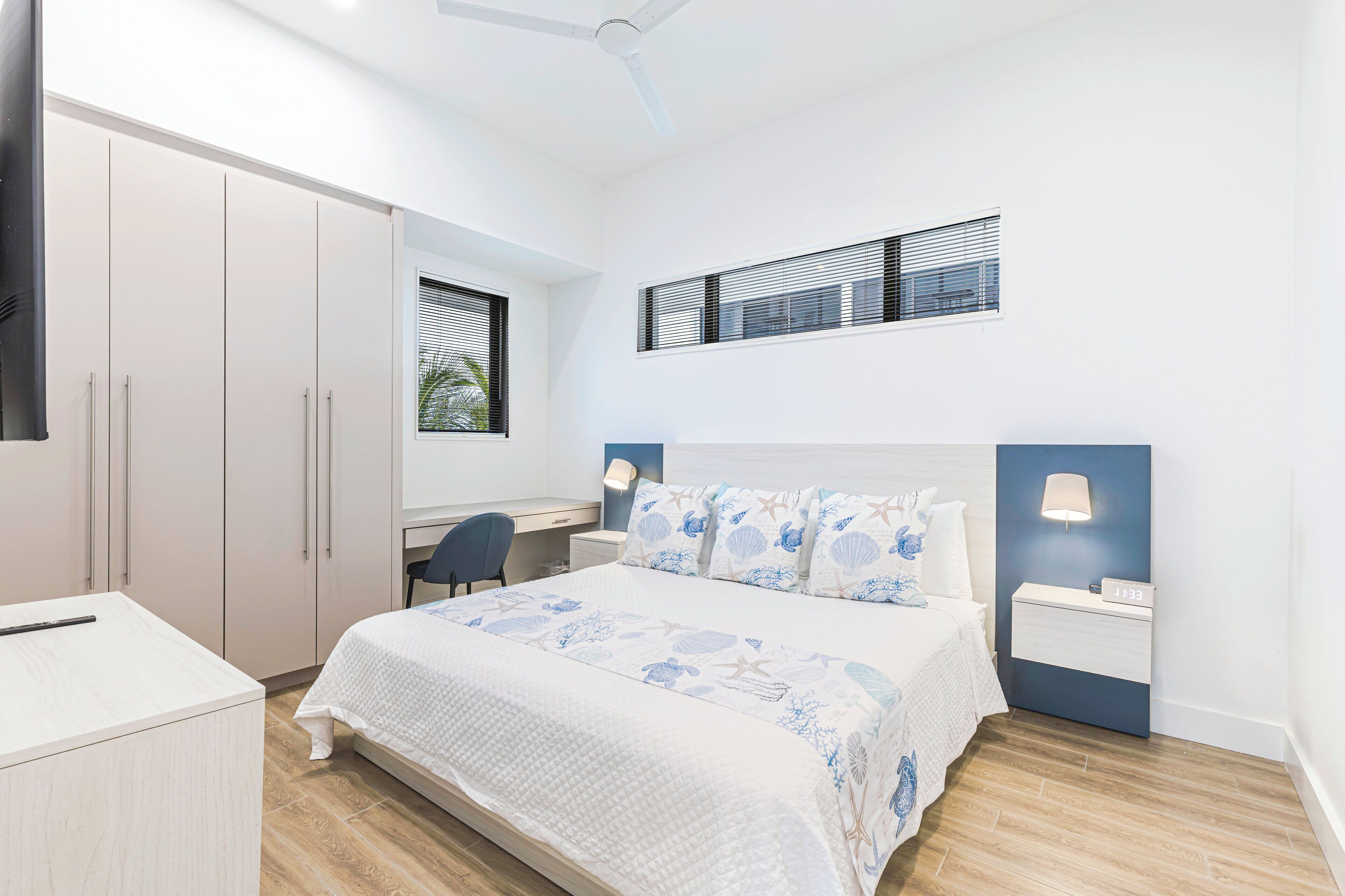 Een slaapkamer met een bed, nachtkastjes, een bureau en een kledingkast.