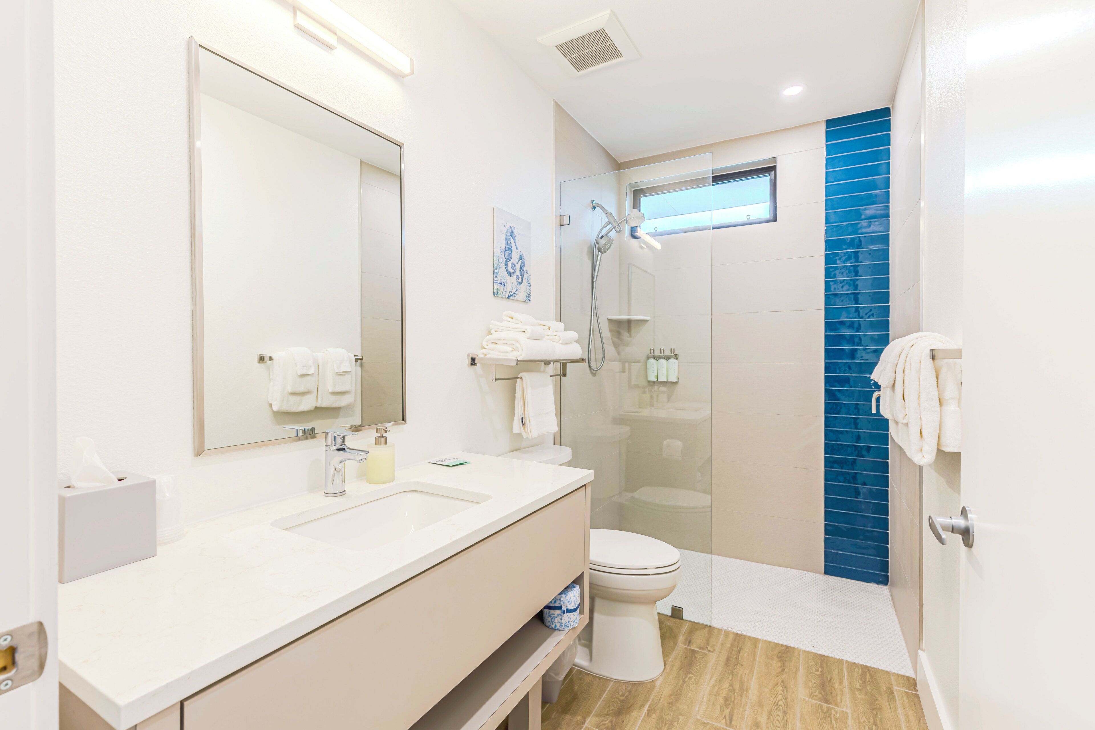 Un bagno moderno con un grande specchio, un lavandino, un water e una doccia.